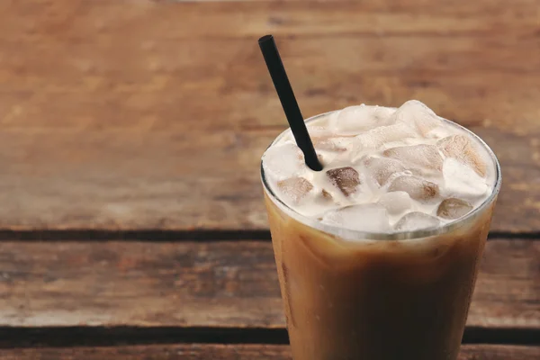 Xícara de café gelado com palha em fundo de madeira — Fotografia de Stock