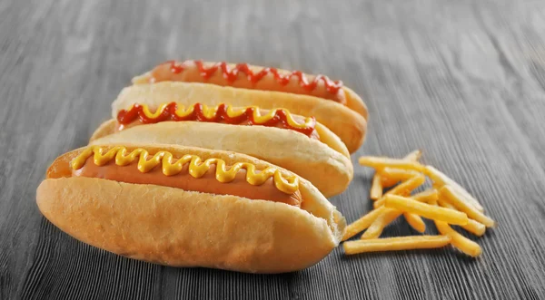 Ízletes hot-dog, hasábburgonyával, fából készült háttér — Stock Fotó