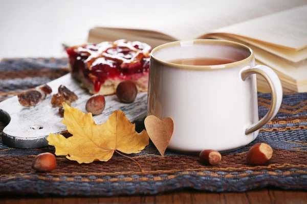 Šálek čaje s podzimní výzdobou na dřevěný stůl. — Stock fotografie