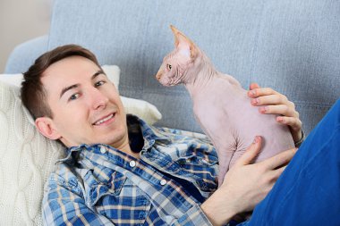 Yakışıklı adam ile kedi kanepede yatıyor
