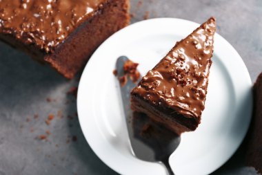 Gri arka plan, beyaz plaka üzerinde fındık kremalı çikolatalı kek lezzetli dilim yakın çekim