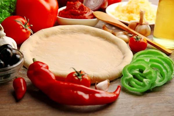 Deeg basis en ingrediënten voor pizza, op de tafel — Stockfoto