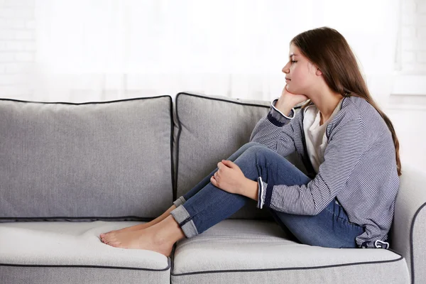 Fille bouleversée assise sur le canapé — Photo