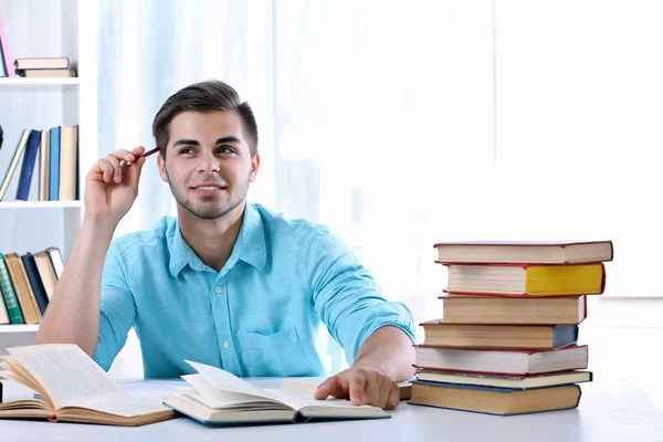 Junger Mann liest Buch am Tisch — Stockfoto