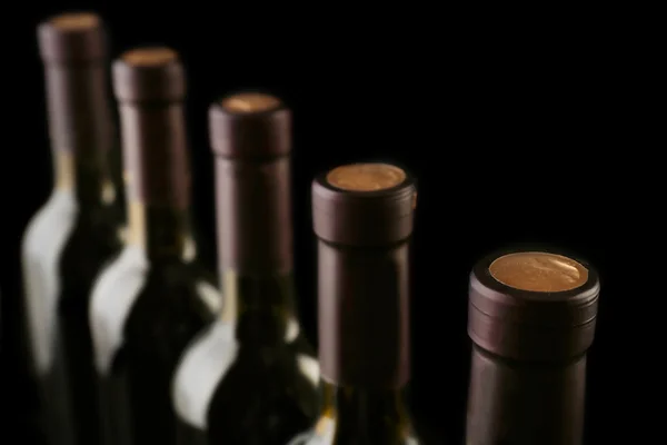 Botellas de vino en fila sobre fondo negro, de cerca — Foto de Stock