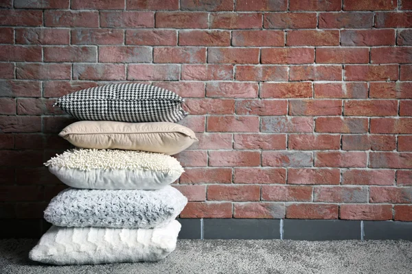 Travesseiros multicoloridos na parede de tijolo — Fotografia de Stock