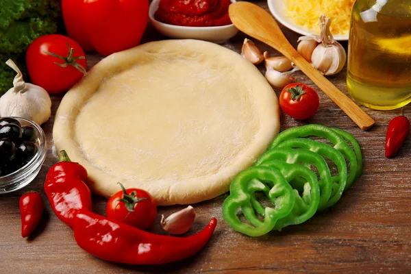 Deeg basis en ingrediënten voor pizza, op de tafel — Stockfoto