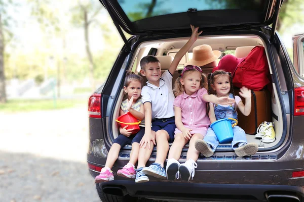 Crianças felizes sentam-se no tronco do carro — Fotografia de Stock