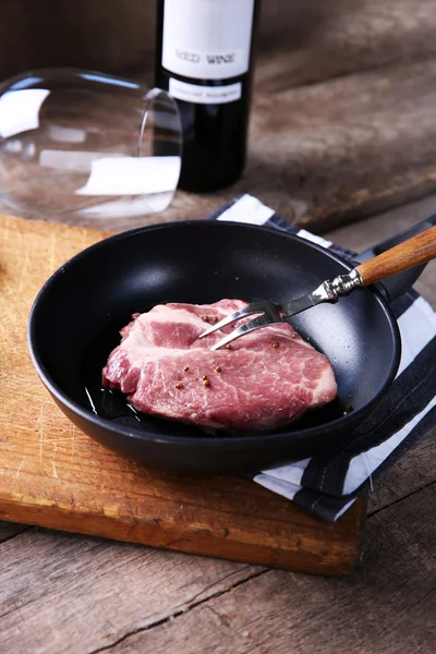 Bife de carne marmorizada e garrafa de vinho no fundo de madeira — Fotografia de Stock