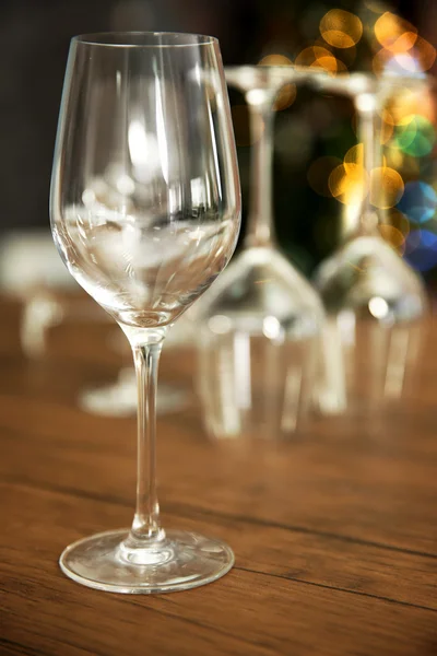 Empty wine glasses on wooden table against blurred background — Stock Photo, Image