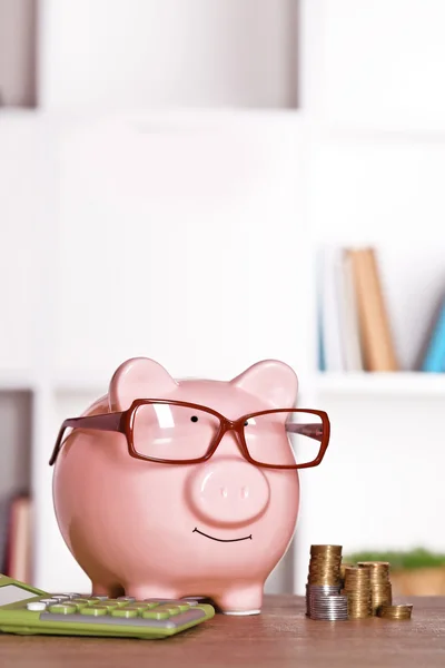 Sparschwein in Brille mit Taschenrechner und Münzen — Stockfoto