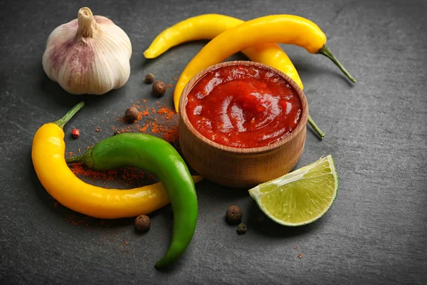 Salsa picante casera y especias sobre fondo oscuro — Foto de Stock