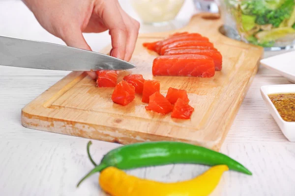 Mulher cortando salmão defumado para salada, na cozinha — Fotografia de Stock