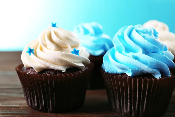 Cupcakes de chocolate sobre mesa de madera delante de fondo azul — Foto de Stock