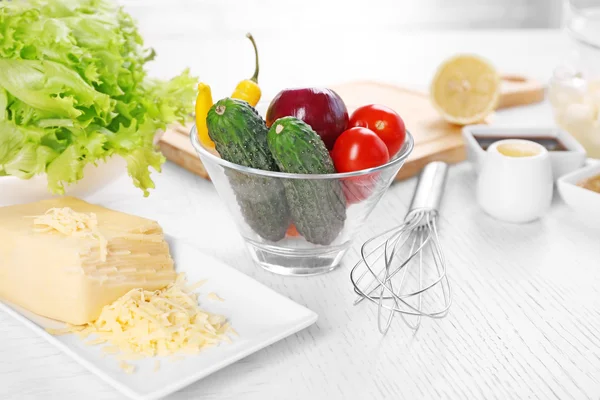 Keukengerei en ingrediënten voor salade op tafel, op lichte achtergrond — Stockfoto