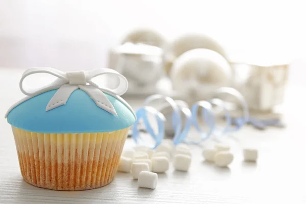 Tasty cupcake with bow, coffee cup and Christmas toys on color wooden background — Stock Photo, Image