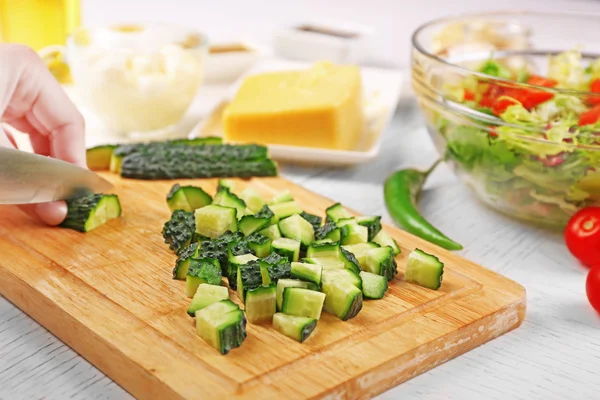 Mani femminili che tagliano verdure per insalata, a cucina — Foto Stock