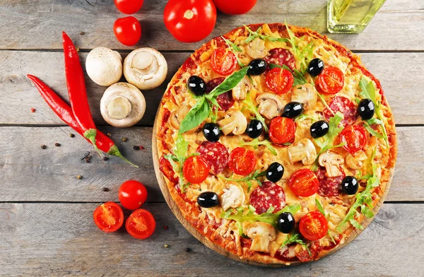 Heerlijke smakelijke pizza met ingrediënten op houten tafel — Stockfoto