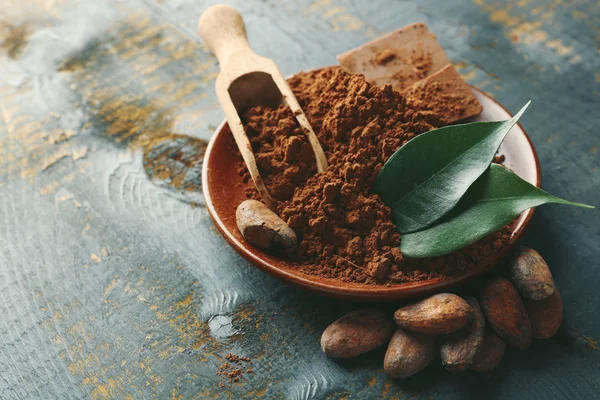 Cuenco con cacao aromático en polvo y hoja verde sobre fondo de madera rayada, de cerca — Foto de Stock