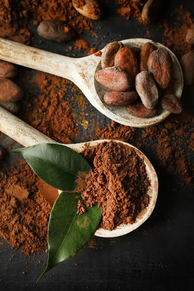 Cuillère avec poudre de cacao aromatique et feuille verte sur fond de bois rayé, gros plan — Photo