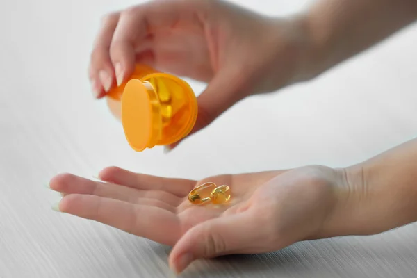 Woman spills yellow medical capsules — Stock Photo, Image