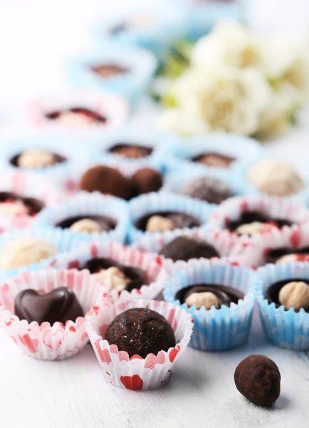 Набор шоколадных конфет с цветами на светлом деревянном фоне, крупный план — стоковое фото