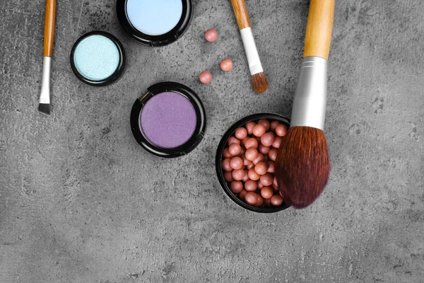 Pinceles de maquillaje, sombra de ojos y colorete, sobre fondo gris — Foto de Stock