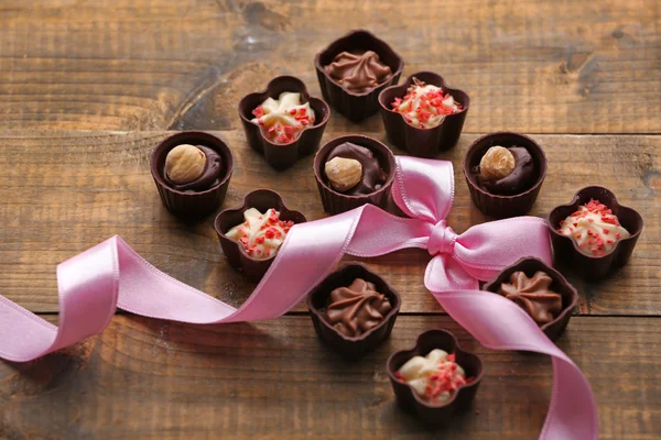 Ensemble de bonbons au chocolat avec ruban sur un fond en bois — Photo