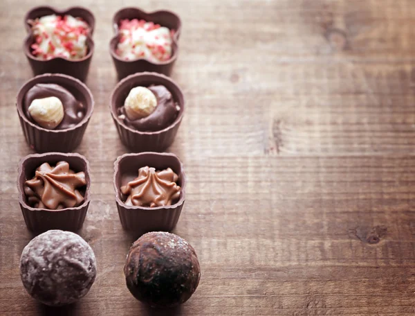 Conjunto de doces de chocolate em um fundo de madeira — Fotografia de Stock