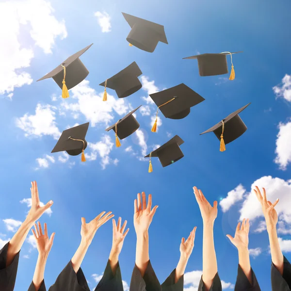 Graduados manos lanzando sombreros de graduación — Foto de Stock