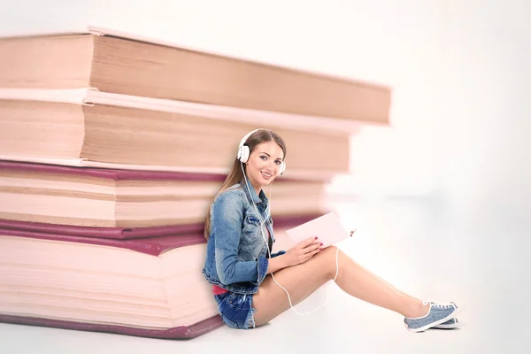 Donna con cuffie vicino pila di libri — Foto Stock