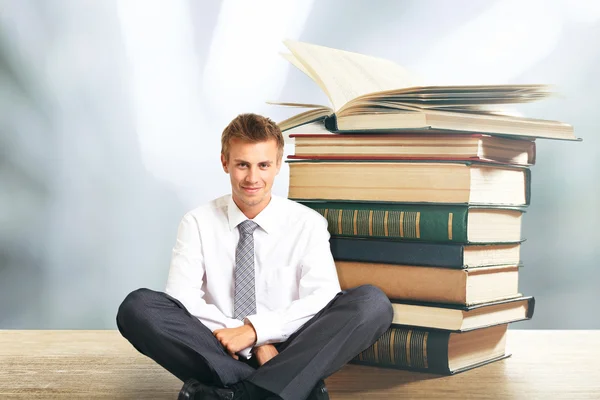 Hombre con portátil sentado cerca de pila de libros —  Fotos de Stock