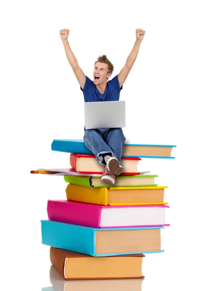 Hombre con portátil sentado en la pila de libros — Foto de Stock