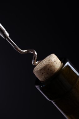 Tirbuşon ve siyah bir zemin üzerine şarap şişesi