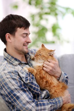 Kabarık kedi ile genç adam oturuyor