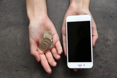 Holding eller gri arka plan üzerinde jetonlu telefon akıllı. Telefon masrafları