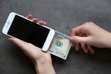Holding eller Doları banknot gri arka plan üzerine telefonla akıllı. Online para yapma