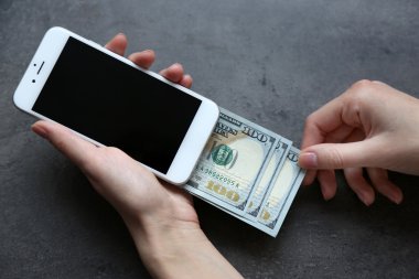 Holding eller Doları banknot gri arka plan üzerine telefonla akıllı. Online para yapma