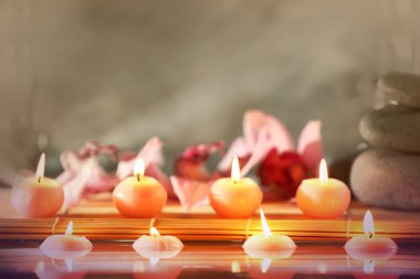 Spa natürmort taşlar, mumlar ve gri arka plan üzerinde su çiçeği.