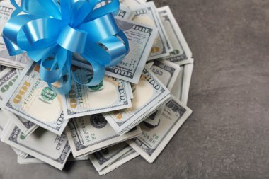 Gri dokulu arka plan üzerinde hediye olarak yay ile dolar yığını