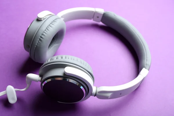 Biały i szary słuchawki na fioletowym tle — Zdjęcie stockowe