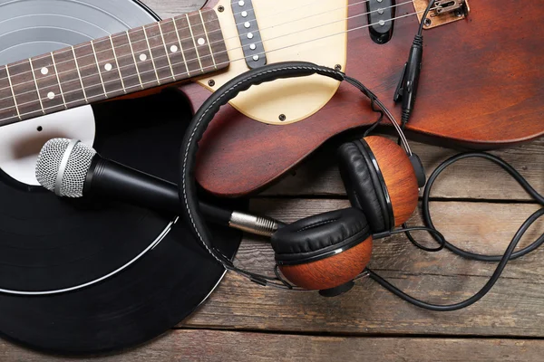 Elektrická kytara a sluchátka s mikrofonem a vinyl na dřevěné pozadí — Stock fotografie