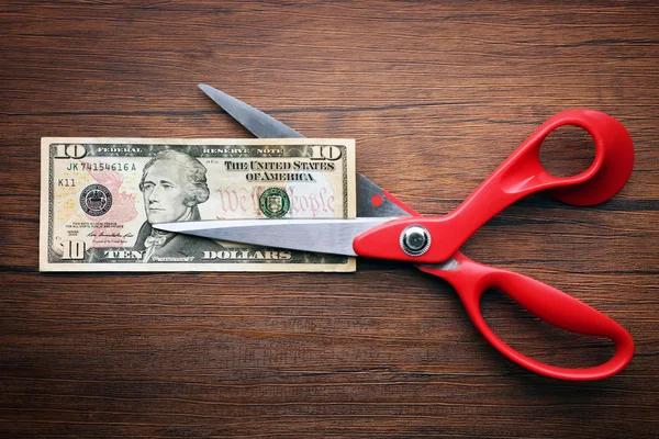 Red scissors cut money