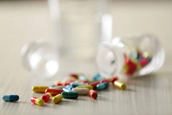Cápsulas coloridas derramadas do frasco da pílula — Fotografia de Stock