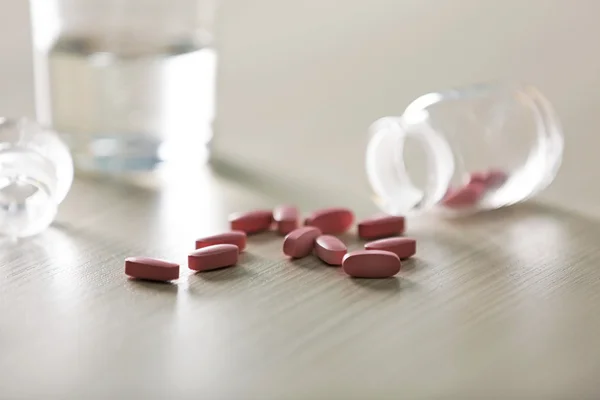 Roze capsules gemorst uit pil fles — Stockfoto