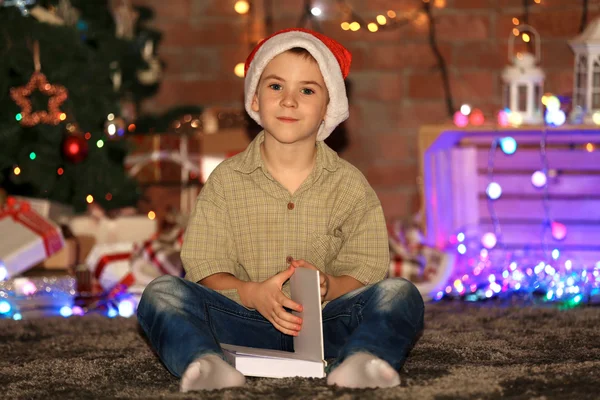 Chlapec s kniha sedí doma na Vánoce — Stock fotografie