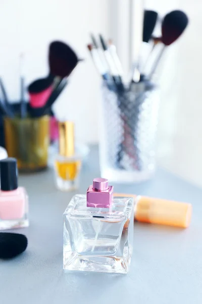 Perfume bottle with makeup tools and cosmetics on a table — Stock Photo, Image