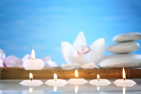 Wellness-Stillleben mit Kerzen im Wasser auf blauem, verschwommenem Hintergrund — Stockfoto