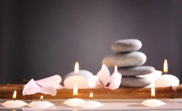 Wellness-Stillleben mit Kerzen im Wasser auf grauem Hintergrund — Stockfoto