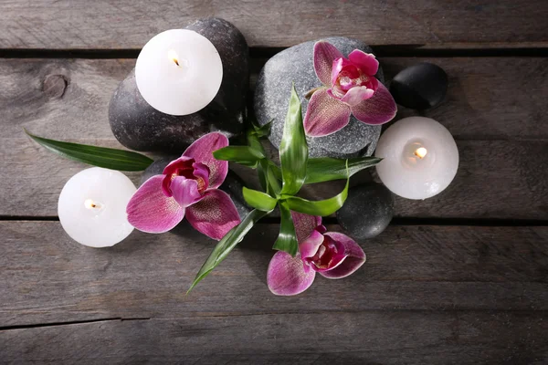 Spa martwa natura z pięknych kwiatów i świec na drewnianym stole, widok z góry — Zdjęcie stockowe